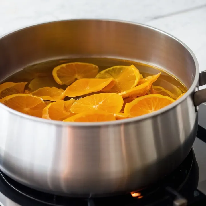 Zanurz przygotowane skórki pomarańczowe w 1 litrze zimnej wody, dodaj 250 g cukru i gotuj na średnim ogniu 20 minut. Dodaj kolejne 250 g cukru i gotuj 15 minut. Powtórz tę operację jeszcze dwukrotnie, zużywając cały pozostały cukier.
