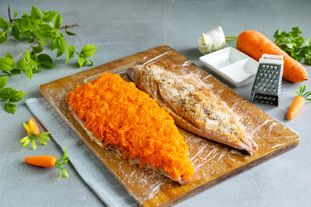 Peel the boiled carrots and shred them on a grater with large holes. Place the grated carrots on one mackerel fillet.
