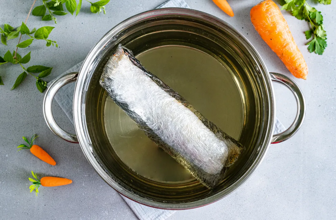 Pour water into a saucepan of appropriate diameter, bring to a boil. Carefully lower the mackerel roll in film into the boiling water, cook it for 30 minutes.
