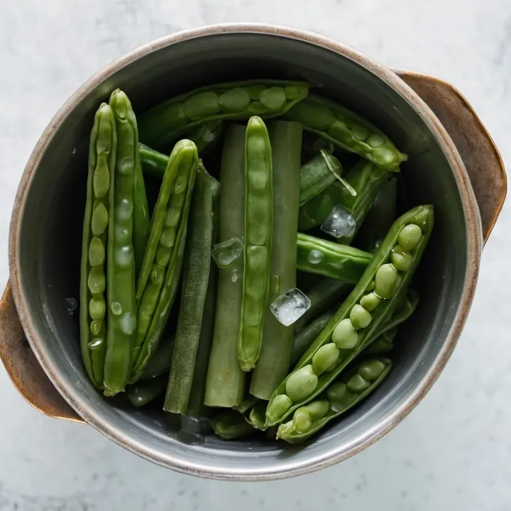 Prepare a deep bowl, filling it with ice water and adding ice cubes for maximum cooling. Drain the cooked beans in a sieve, then immediately transfer them to the bowl with ice water to stop the cooking process. Leave the beans in the ice water for 5 minutes, then drain them again in a sieve to remove excess water.
