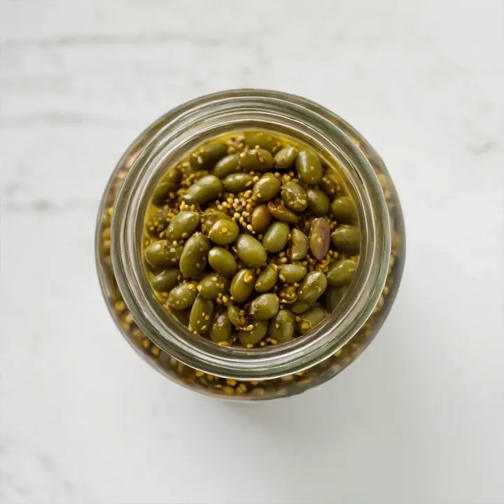 Pour the table vinegar into the boiling marinade, and then immediately remove the saucepan from the heat to preserve the aroma and avoid excessive acidity. Arrange the prepared beans in sterilized jars, trying to distribute them evenly. Carefully pour the hot marinade over the beans, ensuring full coverage. Cover the jars with lids and let them cool completely at room temperature.
