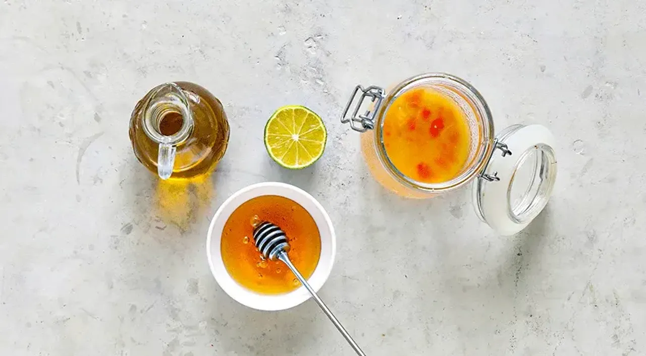 Do przygotowania dressingu wymieszaj w małym słoiku sok pomarańczowy (zebrany podczas krojenia pomarańczy), sok z limonki, płynny miód, oliwę z oliwek i ostry sos sriracha. Dodaj sól i świeżo zmielony czarny pieprz do smaku. Szczelnie zamknij słoik pokrywką i energicznie wstrząśnij, aby wszystkie składniki dobrze się połączyły i utworzyły jednolitą emulsję. Polej sałatkę przygotowanym dressingiem i delikatnie wymieszaj.
