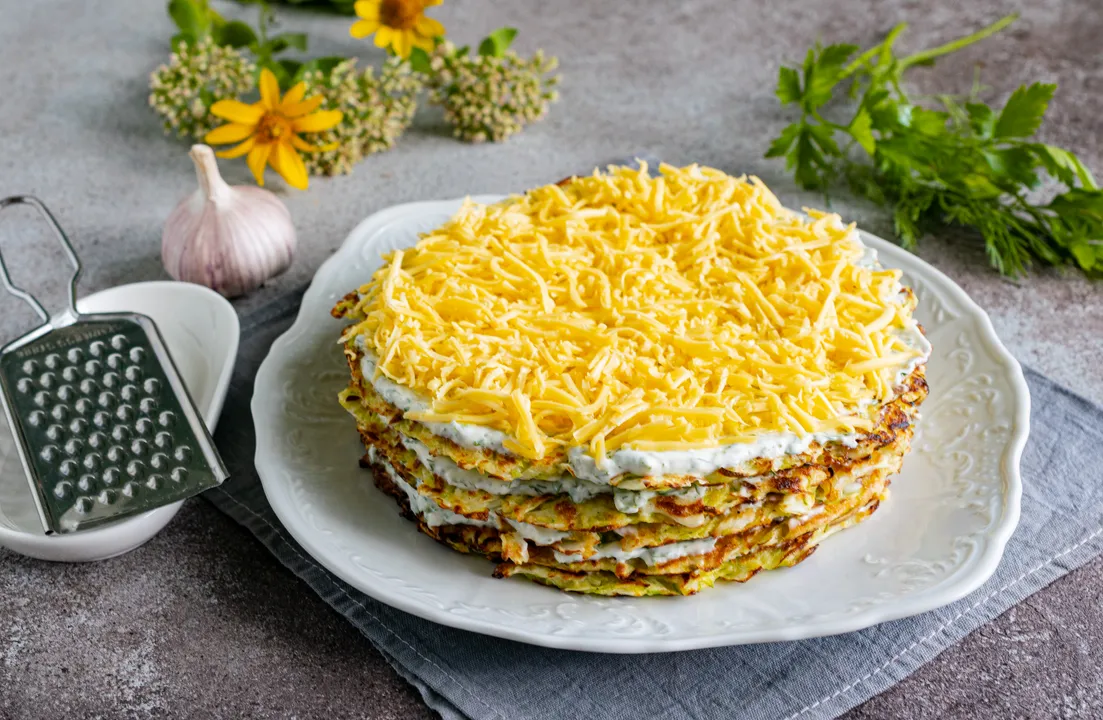 Kendőzd be a felső tortalapot a maradék tejfölös szósszal, díszítsd a torta tetejét reszelt kemény sajttal. Tedd a sós tortát a hűtőszekrénybe legalább 30 percre, hogy összeérjen és lehűljön.
