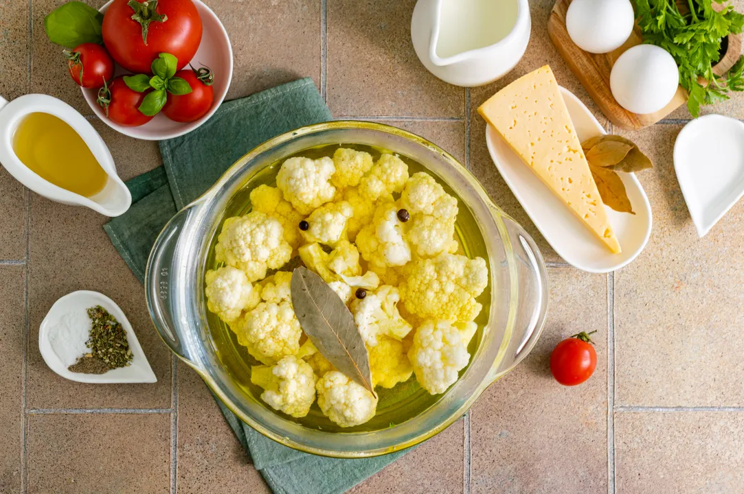 <p>Bring water to a boil in a saucepan. Add salt, allspice, and bay leaf for aroma, ground turmeric for a beautiful golden hue. Carefully lower the cauliflower florets into the boiling water. Cook the vegetables for 3 minutes. Transfer the cauliflower to a colander to drain, cool the vegetables to room temperature.</p>