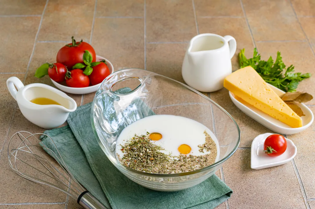 <p>Meanwhile, prepare the filling. In a deep bowl, combine medium-fat cream, chicken eggs, salt, and spices to taste.</p>
