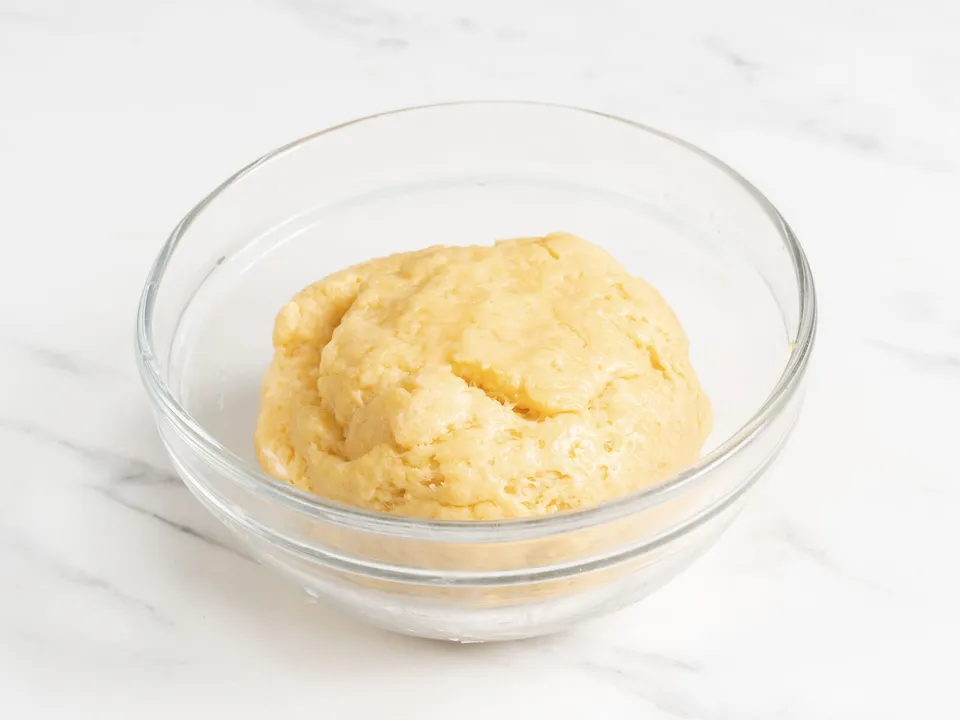 Gradually begin sifting in the flour, adding it to the yolk mixture and continuously stirring the batter with a whisk or spoon.