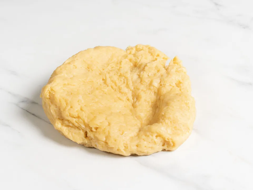 Once the dough is firm enough, knead it by hand in the bowl until smooth.