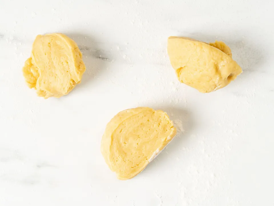 Form the dough into a ball and wrap it in plastic wrap. Leave the dough at room temperature for 30-40 minutes to allow the flour to fully absorb the moisture, making the dough smoother and more pliable.