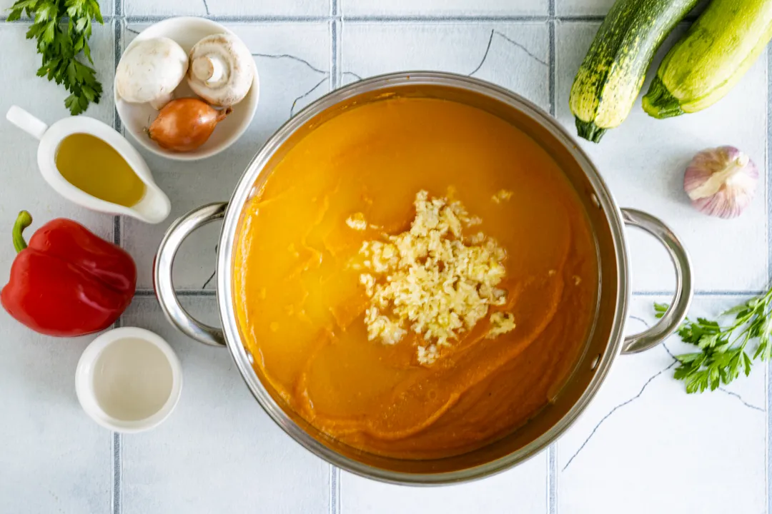 Add the garlic cloves, pressed through a garlic press, to the zucchini caviar. Pour in 9% table vinegar to ensure the preservation keeps well all winter.