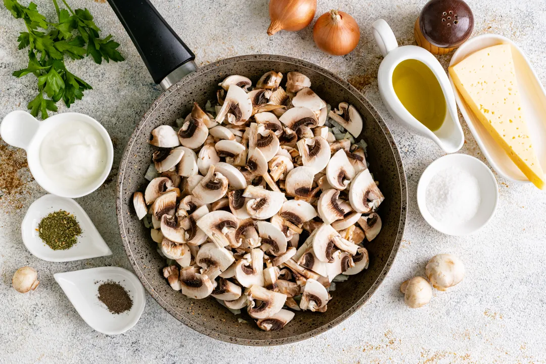 Ezután adja hozzá az apróra vágott gombát a párolt hagymához. Keverje össze, és folytassa az összetevők együttes pirítását, amíg elkészül.