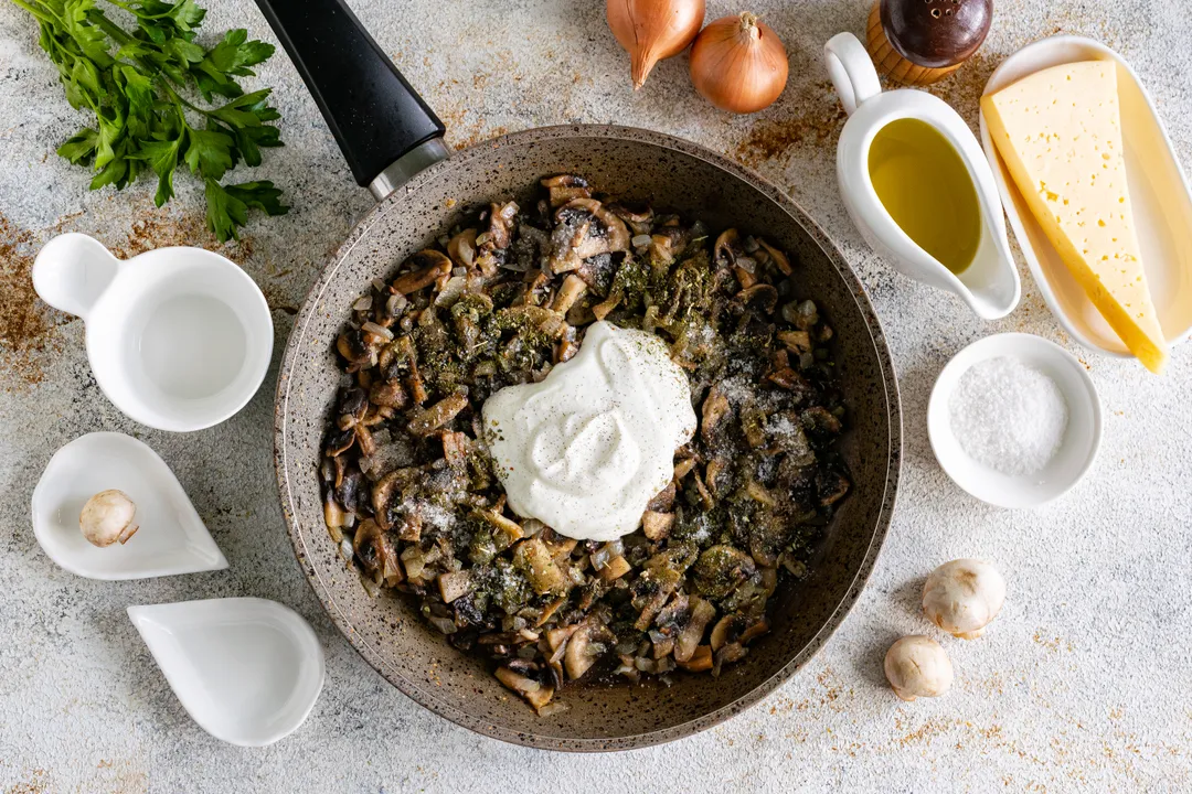 A főzés végén ízlés szerint sózza és fűszerezze. Én őrölt fekete borsot és szárított olasz fűszereket használtam. Adja hozzá a tejfölt, keverje össze. Fedje le a serpenyőt, és párolja a gombát hagymával és tejföllel 5 percig alacsony lángon.