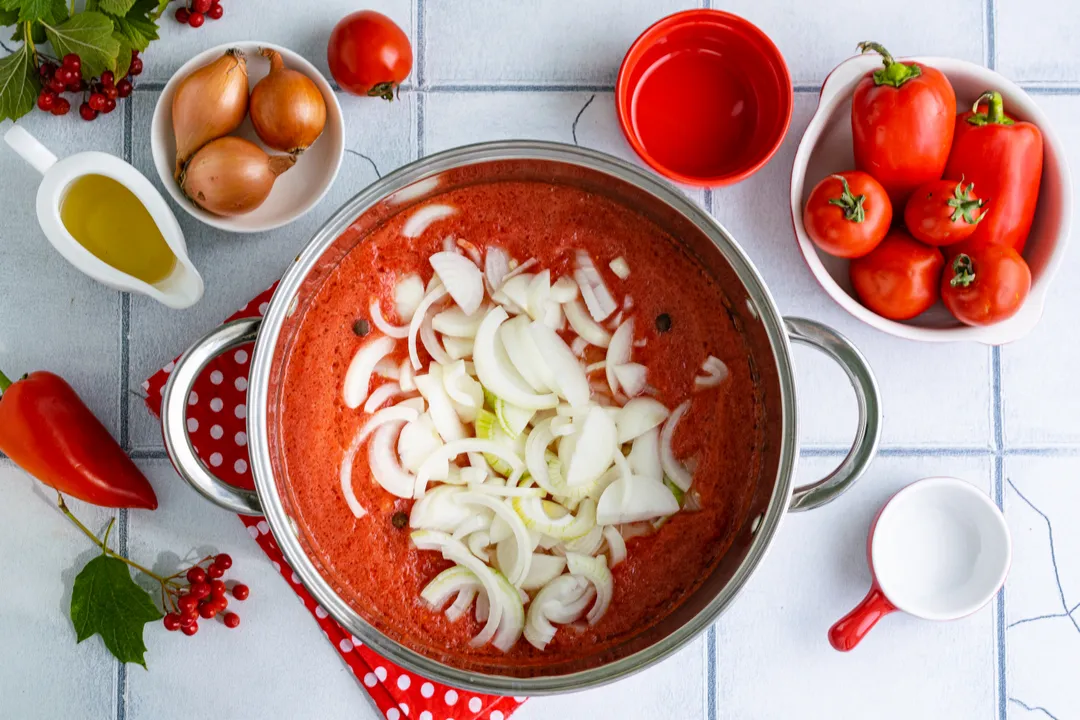 Keverje addig, amíg a száraz hozzávalók teljesen fel nem oldódnak. Fedje le az edényt, és tegye a tűzre. Amikor a paradicsomszósz felforr, adja hozzá az apróra vágott vöröshagymát.