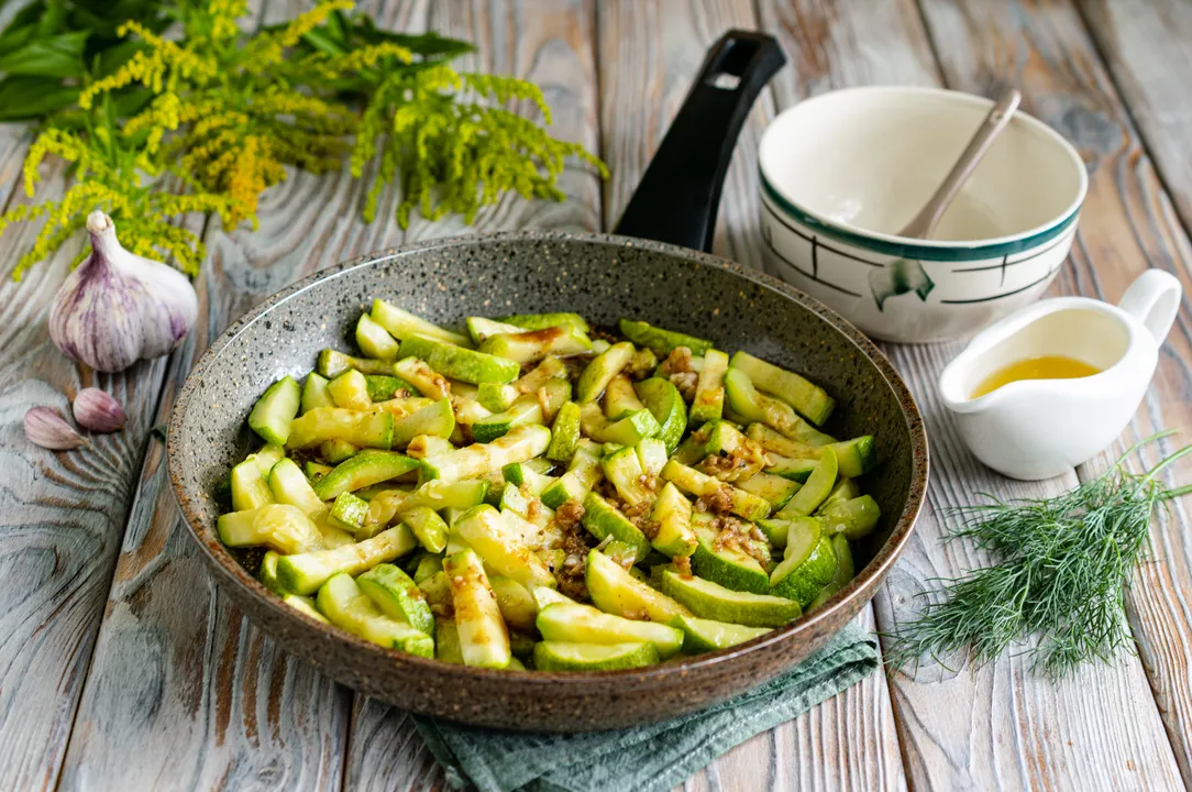 Add soy sauce with garlic, starch, and spices to the fried zucchini. Gently mix the vegetables.