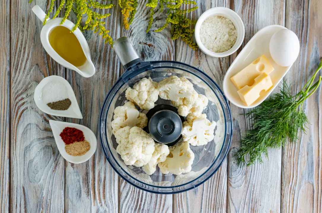 Цвітну капусту помий, розбери на дрібні суцвіття, переклади у чашу блендера. Подрібни овочі до стану дрібної крихти, переклади в глибокий посуд.