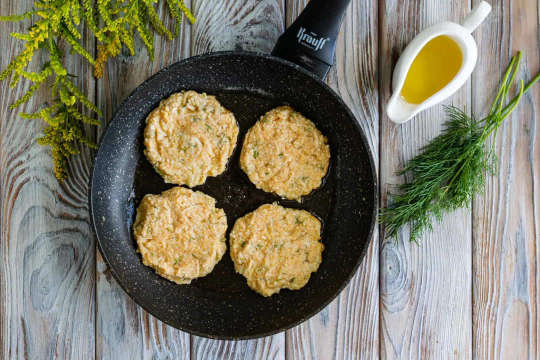 За допомогою столової ложки виклади на сковороду з розігрітою оливковою олією невелику кількість тіста, формуючи круглі оладки завтовшки 1 см.