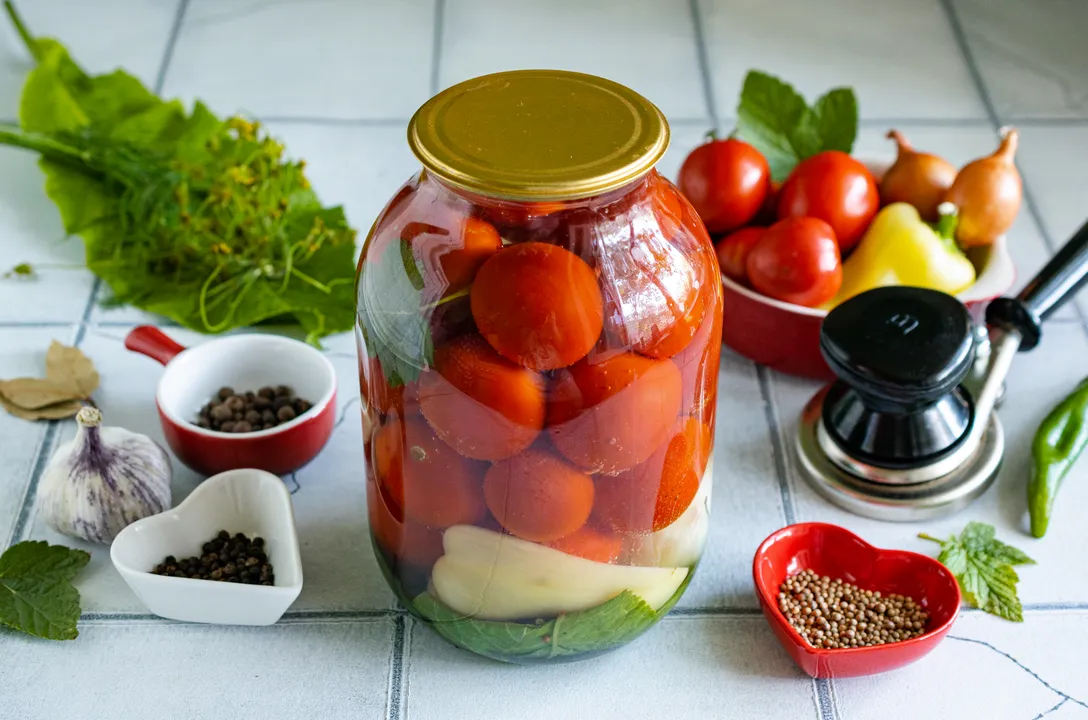 Pour the prepared marinade over the tomatoes in the jars. Cover the jars with lids and seal them with a seaming machine. Turn the canned goods upside down, wrap them in a blanket, and leave them until completely cool.