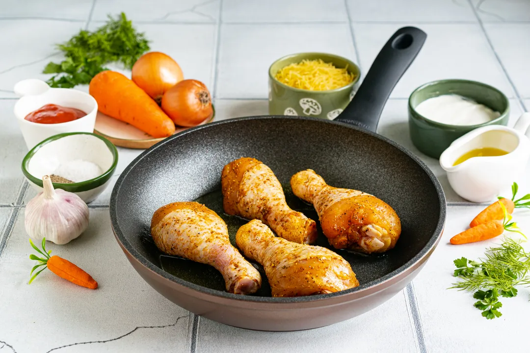 На сковороду з розігрітою оливковою олією викладіть курячі гомілки. Обсмажте м'ясо на середньому вогні до золотистої скоринки з усіх боків.