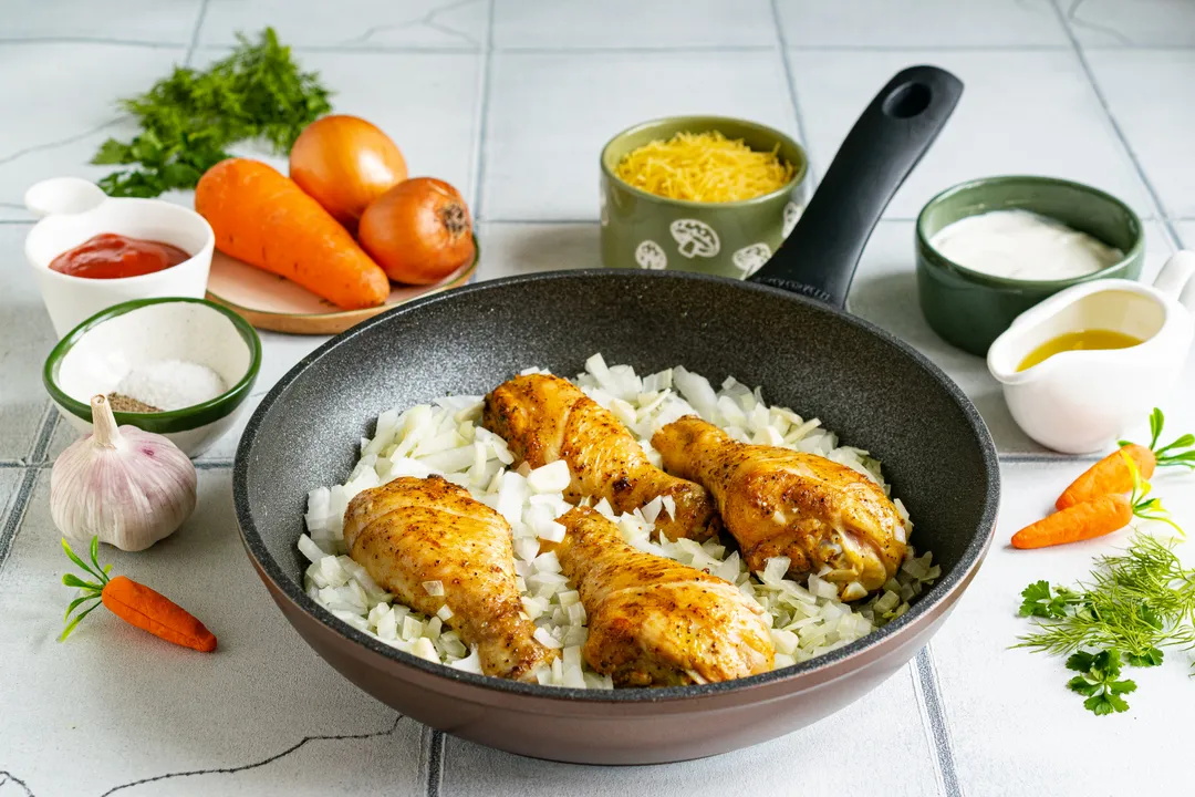 Ріпчасту цибулю очистьте від лушпиння, наріжте невеликим кубиком. Додайте подрібнені овочі до курячих гомілок.