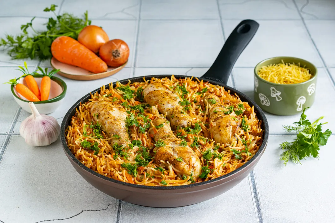 Акуратно перемішайте інгредієнти. Накрийте сковороду кришкою та готуйте вермішель з куркою та овочами на повільному вогні протягом 15 хвилин. Через зазначений час курячі гомілки та вермішель повністю приготуються, а рідина випарується. Прикрасьте готову страву подрібненою зеленню кропу та петрушки.